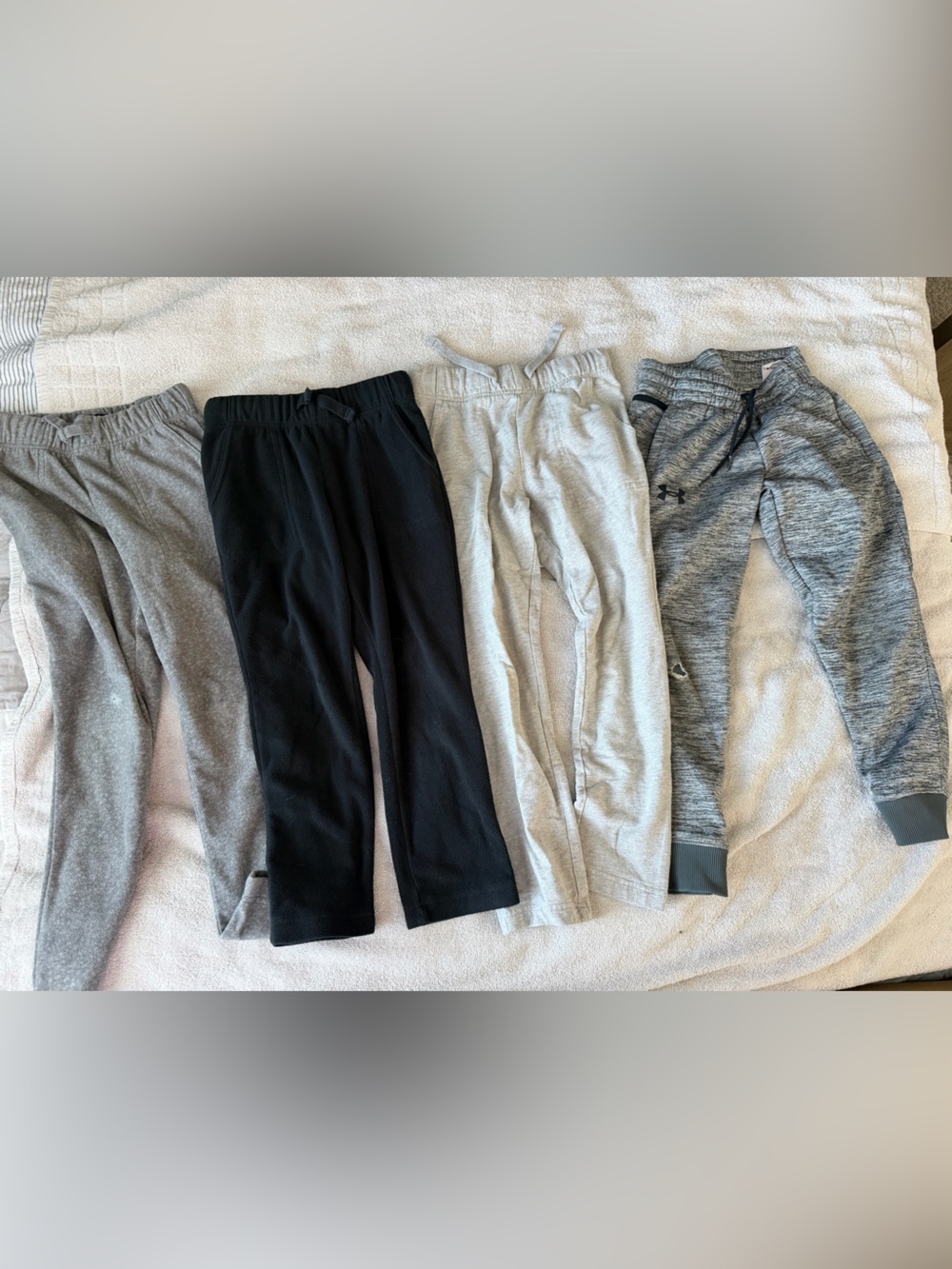 Bundle of joggers with holes at knee and paint on one of them